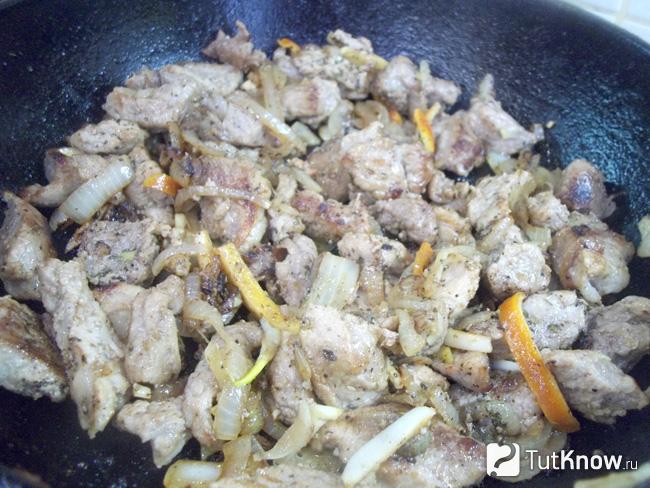 Готовое жареное мясо с луком и апельсиновой цедрой