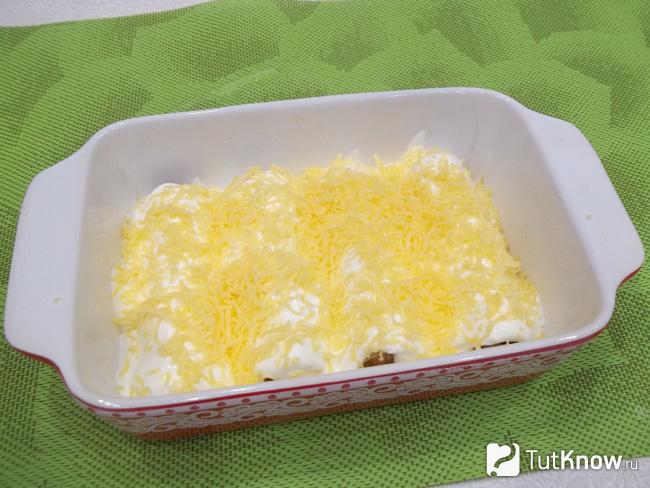 Каннеллони с фаршем и сметанным соусом присыпаны сырной стружкой