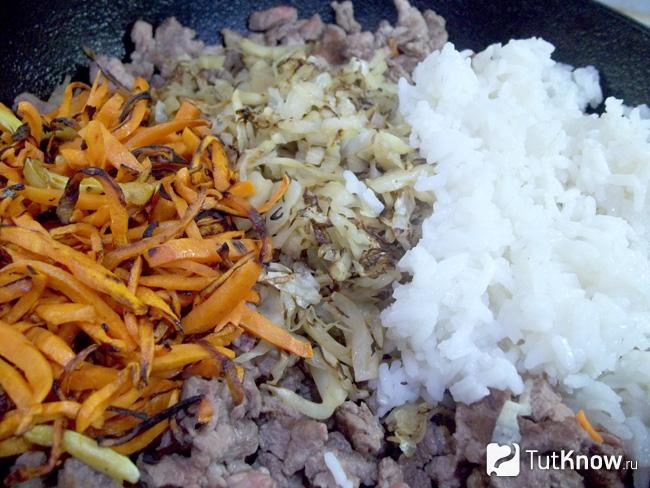 В большой сковороде соединено жареное мясо с жареной капустой, морковью и рисом