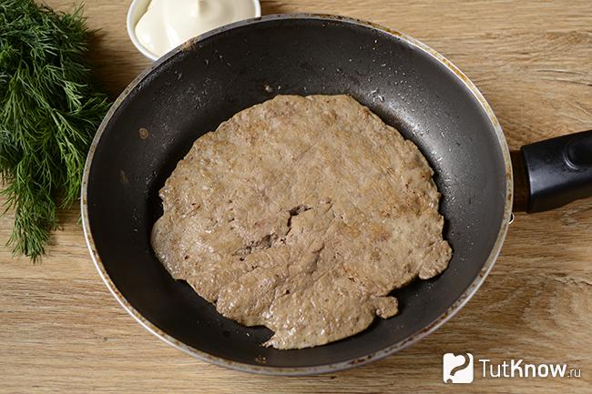 Печёночный блинчик жарится на сковородке