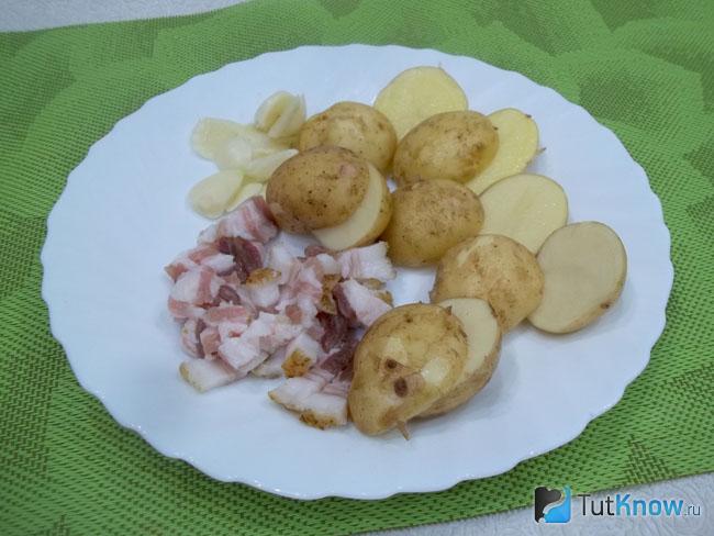 Картофель вымыт и разрезан пополам, чеснок и бекон нарезаны слайсами