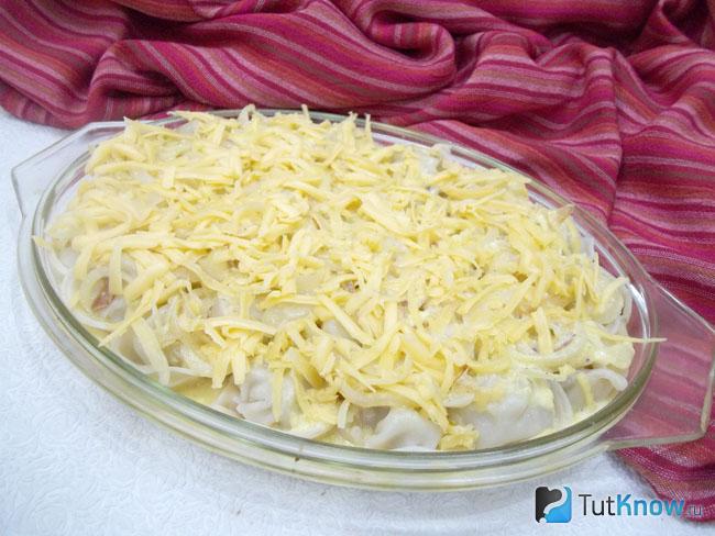 Пельмени залиты яично-сливочным соусом и присыпаны сырной стружкой