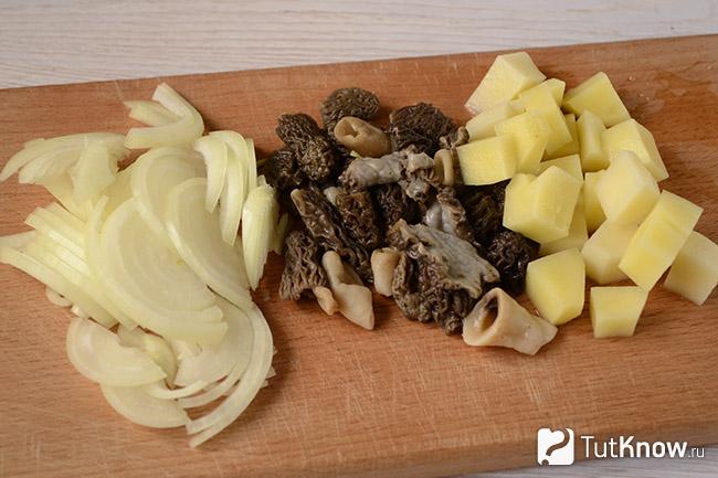 Сморчки, нарезанная картошка и лук на кухонной доске