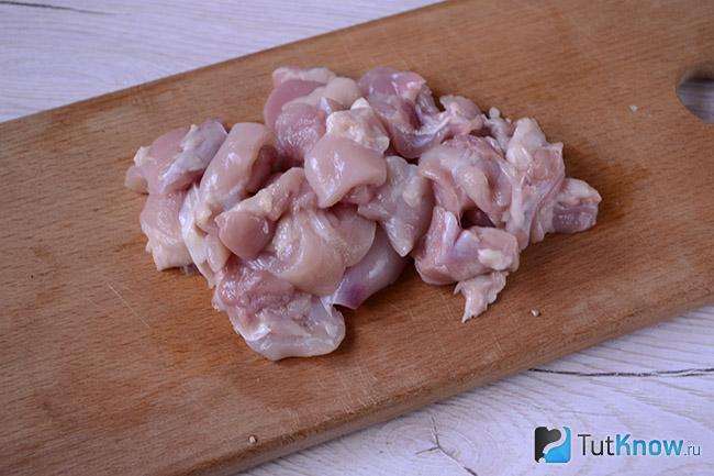 Кусочки куриного мяса на кухонной доске
