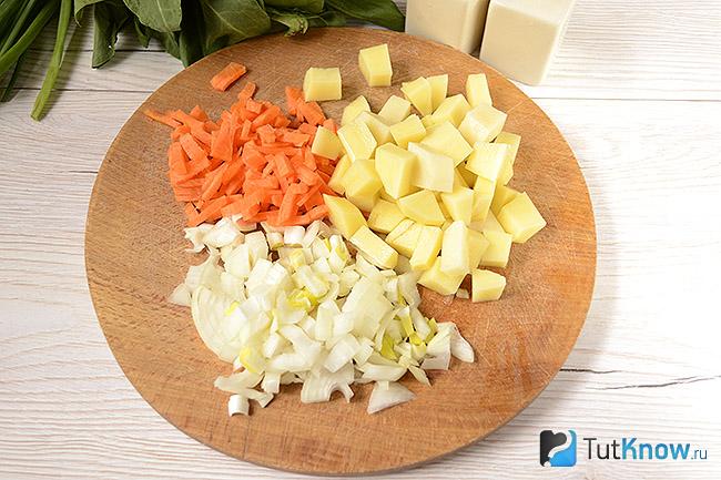 Лук, морковь и картошка порезаны на дощечке