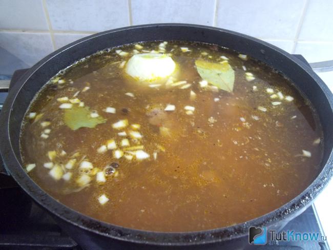 Мясной суп с печенью и овощами варится на плите