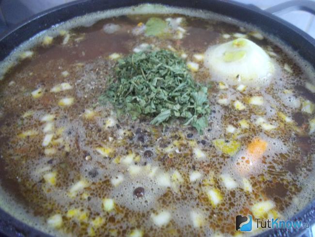 Готовый мясной суп с печенью и овощами приправлен зеленью