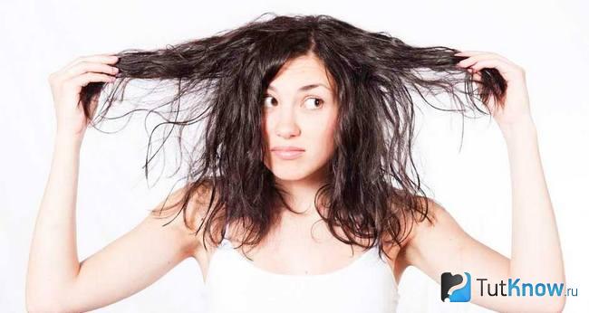 Девушка держит в руках пряди своих волос