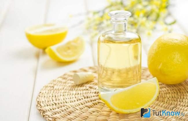 Дольки лимона и бутылочка с лимонным эфирным маслом