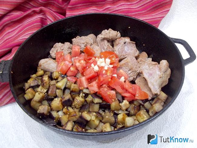 Баклажаны и мясо соединены и добавлены нарезанные помидоры и измельченный чеснок