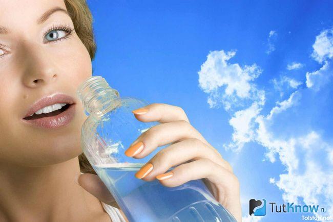 Пьющая воду девушка на фоне неба