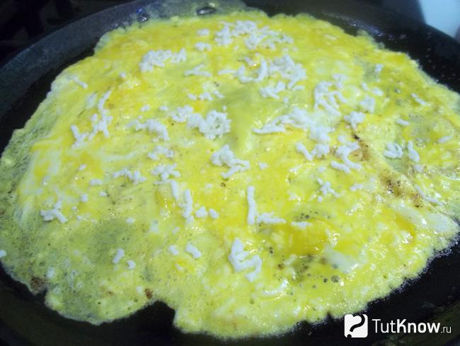 Яичная масса присыпана сыром и омлет с сыром Джейми Оливера готовится на плите 2-3 минуты
