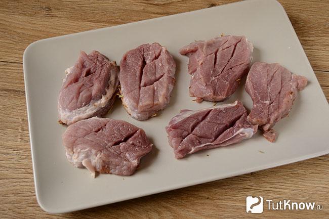 Порезанные кусочки свинины на дощечке