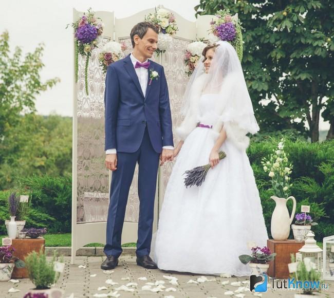 Жених и невеста возле украшенной ширмы