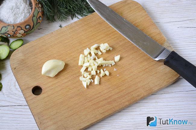 Мелко нарезанный чеснок на кухонной дощечке
