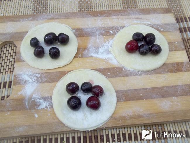 На кружочки теста выложены вишни