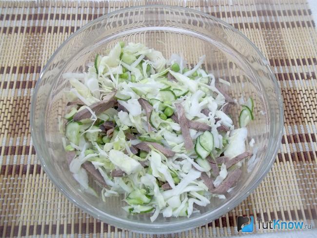 Салат с языком, зеленым горошком, капустой и свежим огурцом заправлен маслом и солью