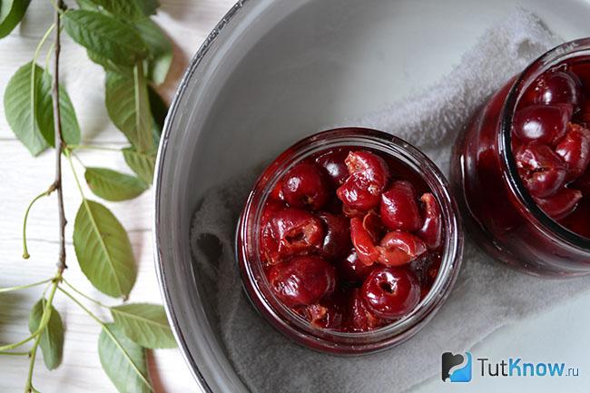 Банки с вишнями стоят в кастрюле