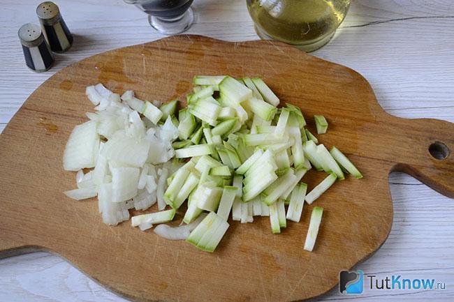 Порезанные кабачок и лук на кухонной доске