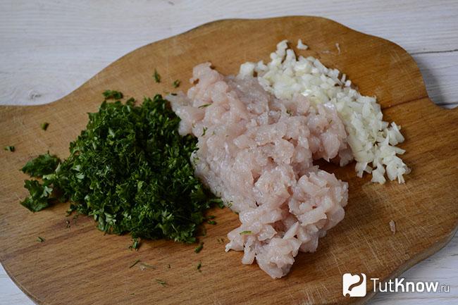 Измельченное куриное филе, зелень и лук на кухонной доске