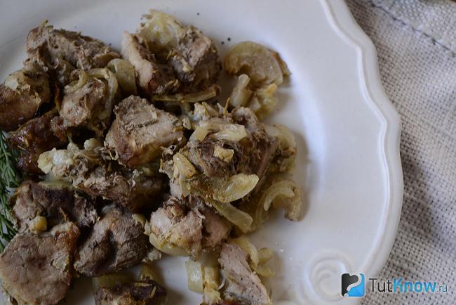 Свинина кусочками с луком на тарелке