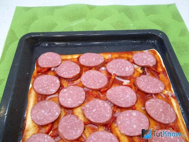 На тесто выложен нарезана нарезана кольцами колбаса