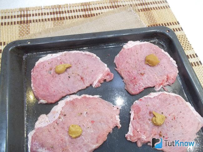 Мясо выложено на противень, приправлено солью и горчицей