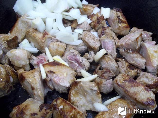 Мясо с луком жарится на сковороде