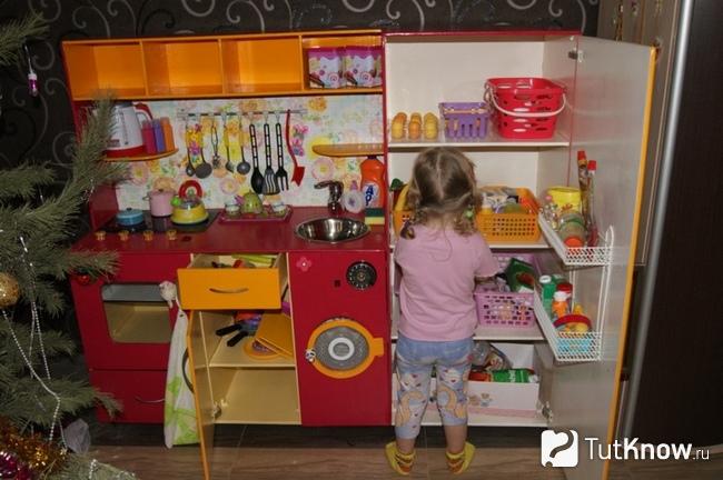 Девочка играется на детской кухне