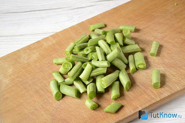 Стручковая фасоль нарезана на кухонной дощечке