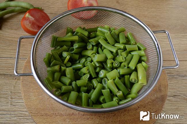 Кусочки стручковой фасоли на дуршлаге