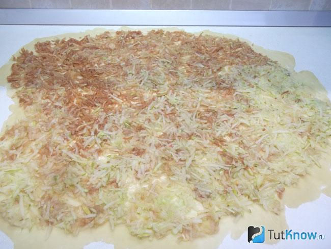На тесто выложены натертые яблоки с грушами