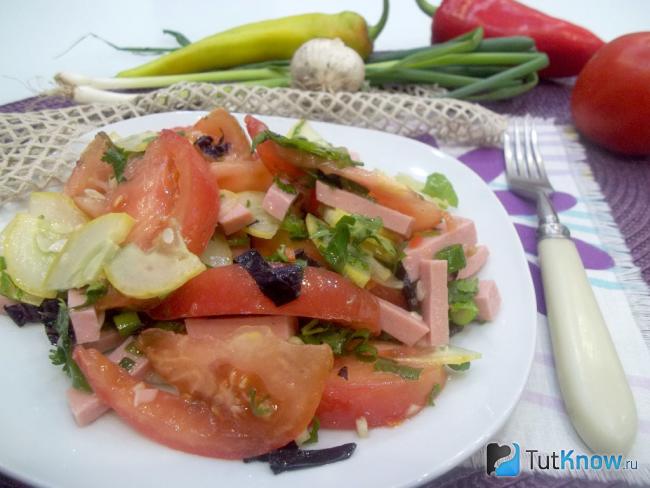 Готовый салат с помидорами, огурцами, колбасой и зеленью