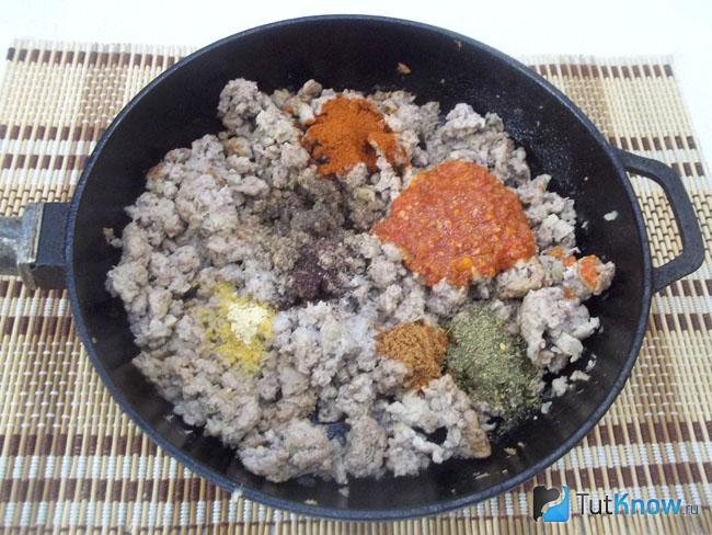 Мясо с луком жарятся в сковороде, к продуктам добавлен томатный соус и специи