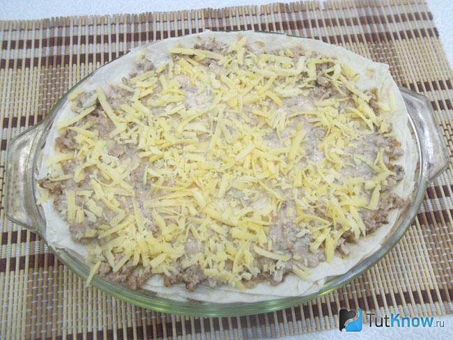 На грибы выложен лаваш, сверху мясной фарш, соус и сыр