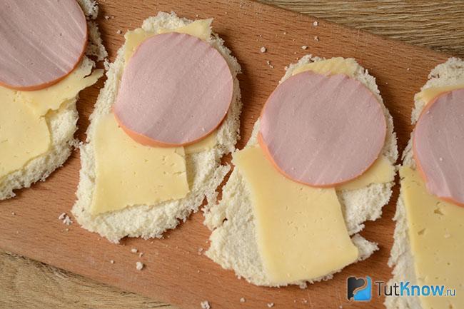Колбаса и кусочки сыра выложены на куски хлебной мякоти