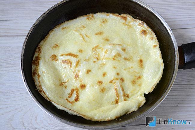 Яичный блинчик жарится на сковороде