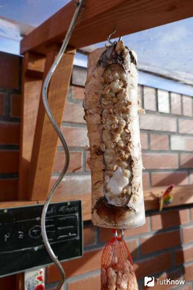 Кормушка из бревна подвешена на крюке