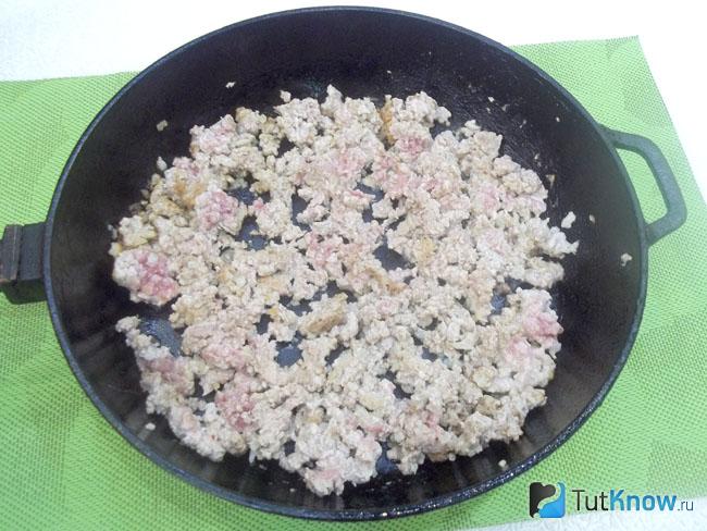 Перекрученное мясо и репчатый лук жарятся в сковороде