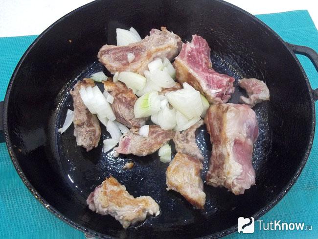 Нарезанное мясо и лук жарятся в сковороде
