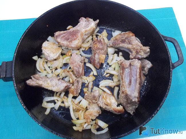 Нарезанное мясо и лук жарятся в сковороде