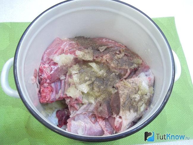 Мясо сложено в кастрюлю, добавлен лук, чеснок и пряности