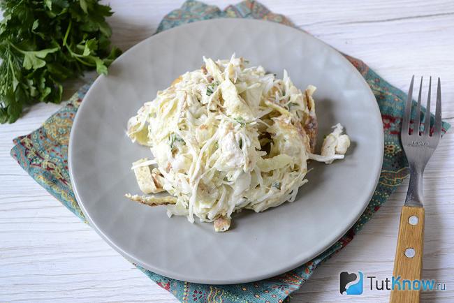 Салат с капустой и яичными блинчиками выложен на тарелке