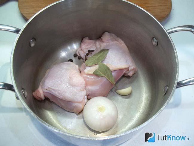 Бедрышки и лук сложены в кастрюлю