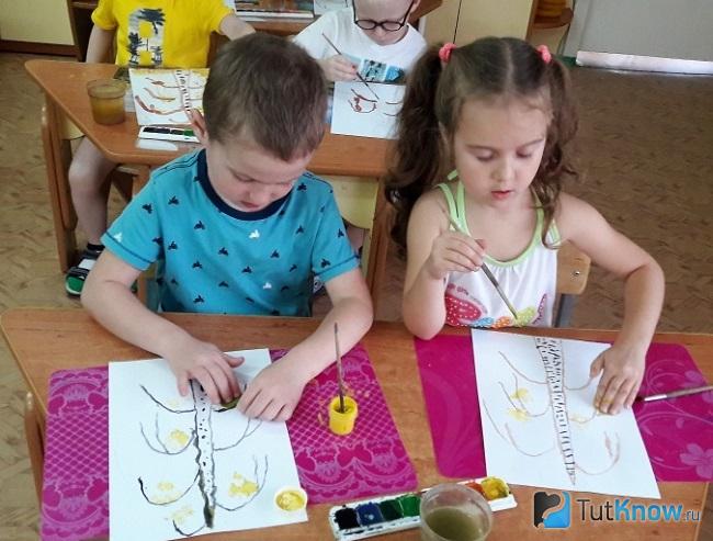 Мальчик и девочка за партой делают поделку
