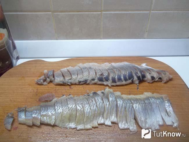 Селедка очищена от костей, извлечен хребет и нарезана кусочками