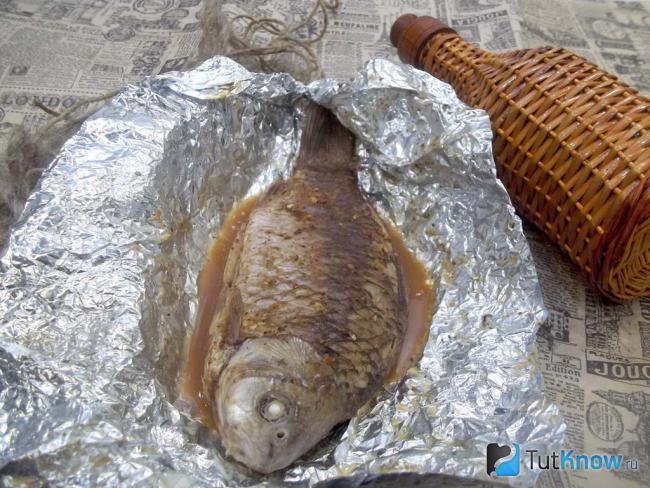 Готовый пряный карась в фольге на сковороде