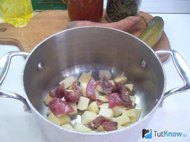 Мясо и очищенный картофель сложены в кастрюлю