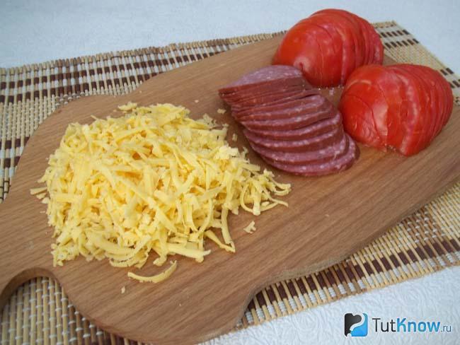 Сыр натерт на терке, колбаса и помидоры нарезаны кольцами