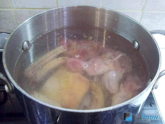 Курица сложена в кастрюлю и залита водой
